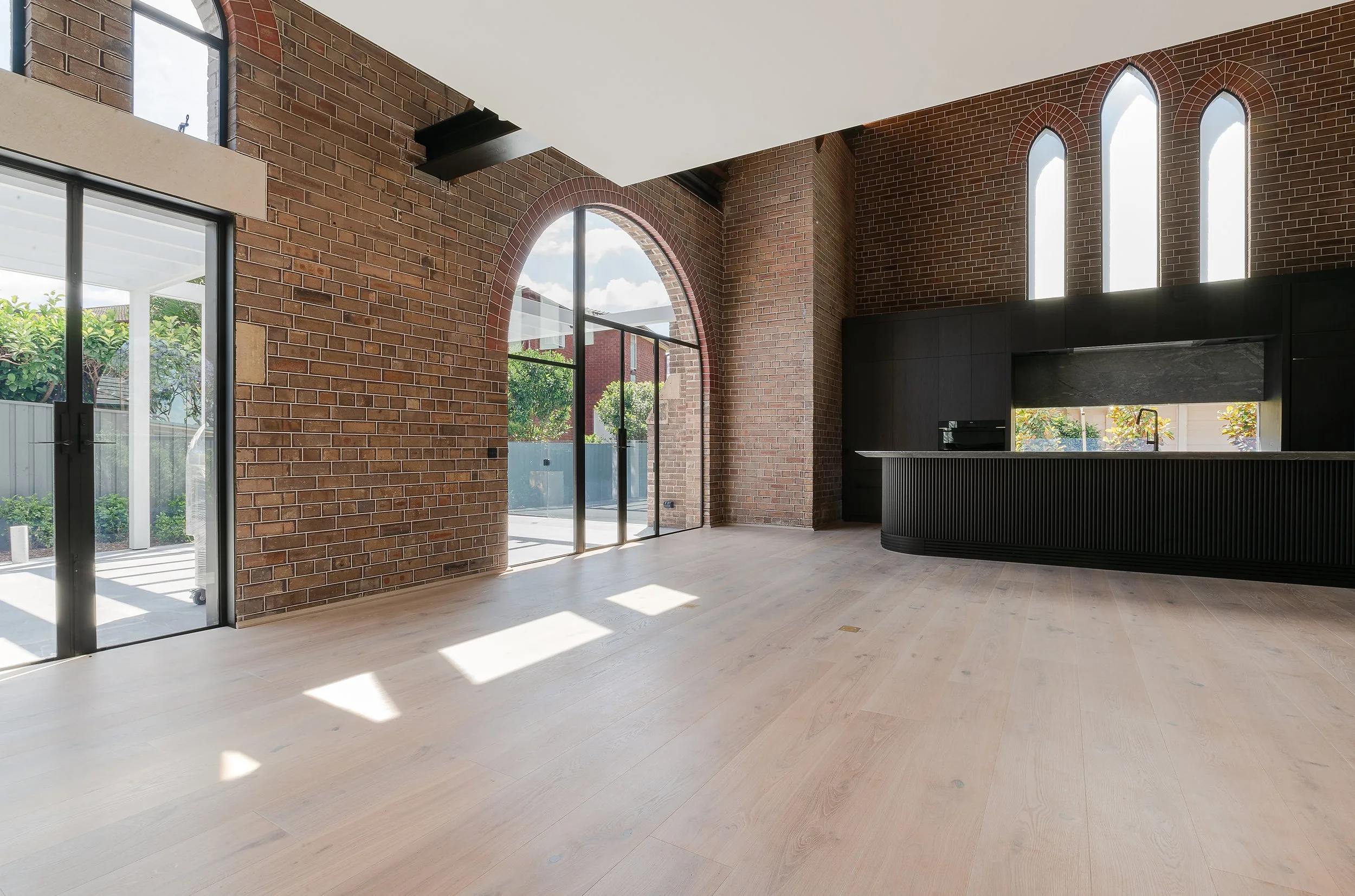 Woolwich church conversion — living space with brick arches and steel-framed glazing